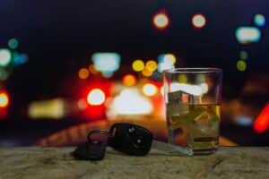 Image is of a pair of keys next to a glass of alcohol against a nighttime background, concept of What is the average cost of a DUI conviction in Nashville?