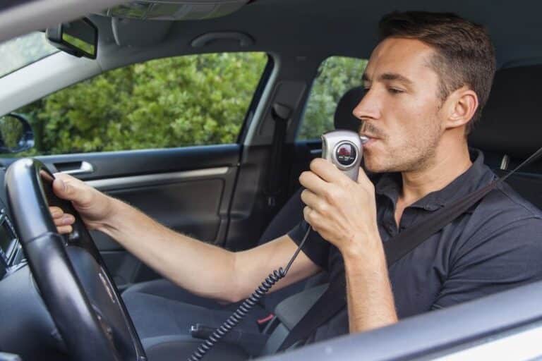 Image is of a man blowing into an ignition interlock device in order to use his car following a DUI conviction, concept of can i get a hardship license in Tennessee?